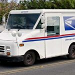 USPS delivery truck driving on urban street.