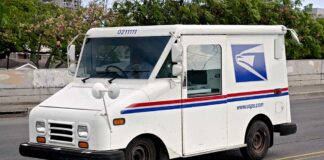 USPS delivery truck driving on urban street.