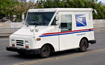 USPS delivery truck driving on urban street.