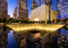 911 Memorial at night with surrounding city buildings.