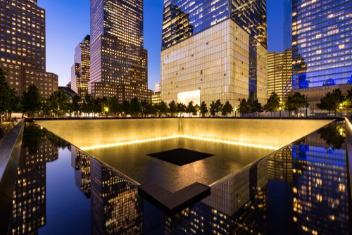 911 Memorial at night with surrounding city buildings.