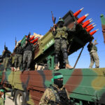 Armed soldiers on a truck with mounted missiles.