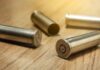 Four empty bullet casings on a wooden surface.