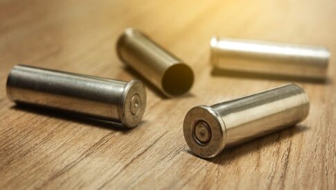 Four empty bullet casings on a wooden surface.