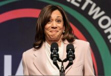 A woman in a light suit speaks at a podium.