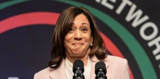 A woman in a light suit speaks at a podium.