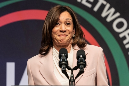 A woman in a light suit speaks at a podium.