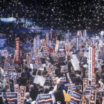 Crowd holding Clinton signs at a political rally.