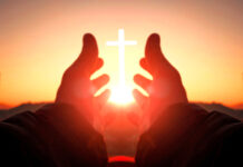 Hands reaching toward sun and cross at sunrise.