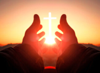 Hands reaching toward sun and cross at sunrise.