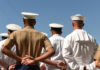 People in military uniforms standing with hands behind backs.