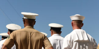 People in military uniforms standing with hands behind backs.