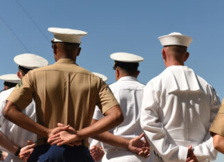 People in military uniforms standing with hands behind backs.