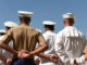 People in military uniforms standing with hands behind backs.