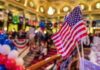 American flags at indoor patriotic event with balloons.