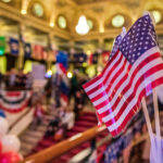 American flags at indoor patriotic event with balloons.