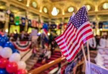 American flags at indoor patriotic event with balloons.