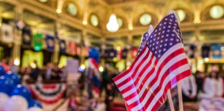 American flags at indoor patriotic event with balloons.