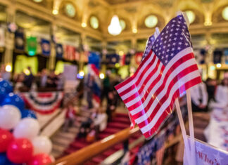 American flags at indoor patriotic event with balloons.