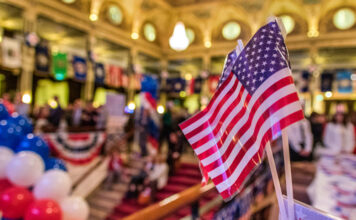 American flags at indoor patriotic event with balloons.