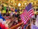 American flags at indoor patriotic event with balloons.