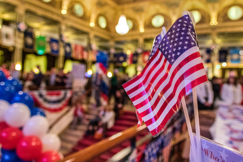 American flags at indoor patriotic event with balloons.