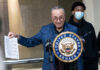 Chuck Schumer holds document at United States Senate podium.