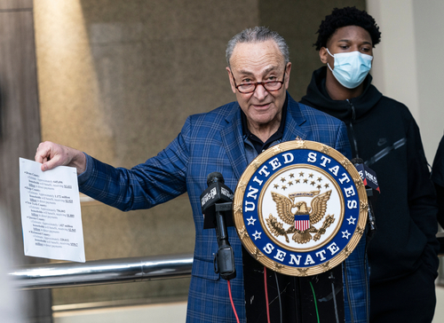 Chuck Schumer holds document at United States Senate podium.