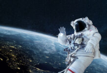 Astronaut floating in space above Earth, waving.