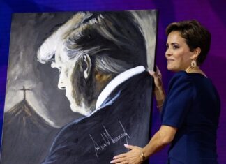 A woman holding a painting of Donald Trump.