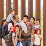 Group of people standing by a metal fence.