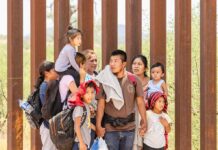 Group of people standing by a metal fence.