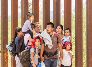 Group of people standing by a metal fence.