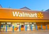 Walmart store entrance with blue bollards at dusk.