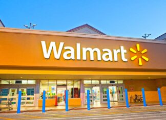 Walmart store entrance with blue bollards at dusk.