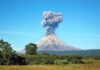 Volcano erupting with thick smoke plume.