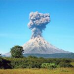 Volcano erupting with thick smoke plume.