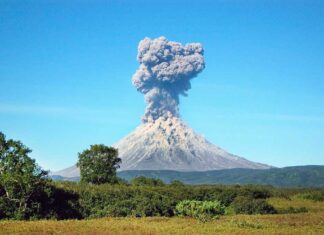 Volcano erupting with thick smoke plume.