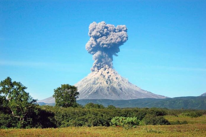 Volcano erupting with thick smoke plume.