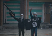 Two masked individuals with a weapon and ISIS flag.