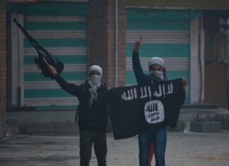 Two masked individuals with a weapon and ISIS flag.