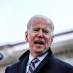 A man speaks into a microphone outdoors.