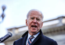 A man speaks into a microphone outdoors.