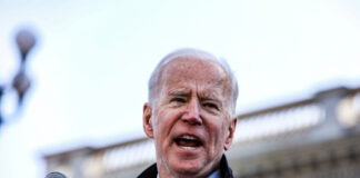 A man speaks into a microphone outdoors.