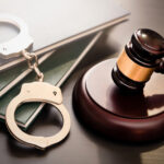 Gavel, handcuffs, and legal books on a dark surface.