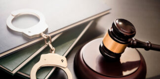 Gavel, handcuffs, and legal books on a dark surface.