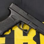 Black handgun on a yellow and black background.