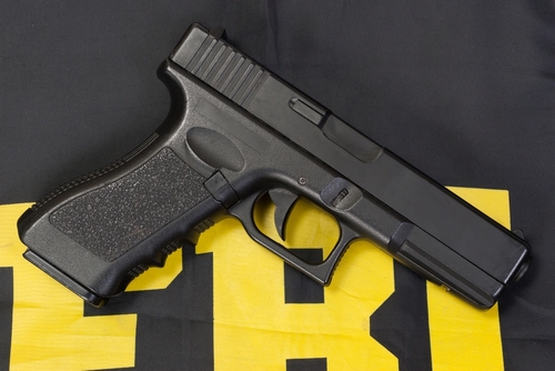 Black handgun on a yellow and black background.