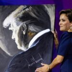 A woman holding a painting of Donald Trump.