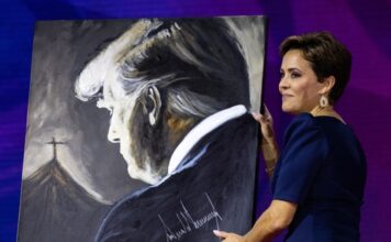 A woman holding a painting of Donald Trump.